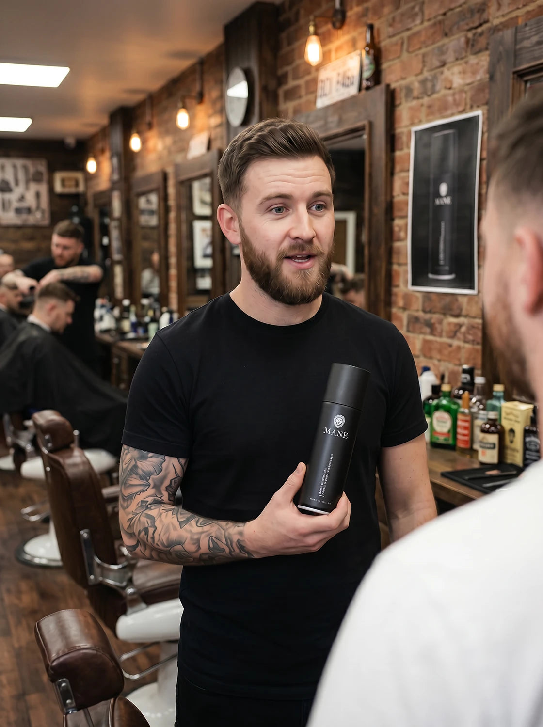 A barber recommending Mane Ahir Thickening Spray to a customer. Mane is the worlds no.1 Cosmetic Hair Thickener.